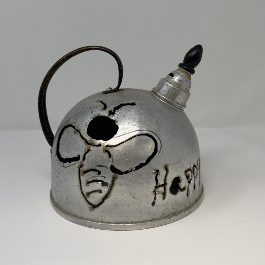 Metal teapot with a face design and 'Happy' engraving on a white background